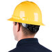 A man wearing a yellow Cordova Duo full-brim hard hat with a 6-point ratchet suspension.