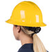A woman wearing a Cordova Duo safety yellow hard hat with a ponytail.
