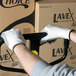 A man wearing Cordova white gloves using a hand truck to move boxes.