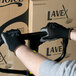 A man wearing Cordova black nylon gloves with gray palm coating holding a box.