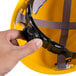 A hand holding a yellow Cordova Duo hard hat with a black strap.