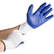 A pair of hands wearing blue and white Cordova work gloves.