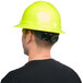 A man wearing a green hard hat with a full brim and ratchet suspension.