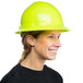 A woman wearing a hi-vis green Cordova hard hat with a full brim and ratchet suspension smiling.