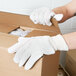 A person wearing Cordova white work gloves opening a box.