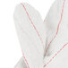 A close up of a Cordova white cotton work glove with red stitching.