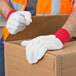 A person wearing Cordova red work gloves opening a cardboard box.