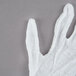 A Cordova white cotton glove on a gray surface.