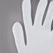 A pair of white Cordova polyester/cotton gloves on a gray surface.