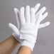 A pair of hands wearing white Cordova polyester/cotton gloves.