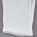 A pair of white Cordova polyester/cotton gloves folded on a gray surface.