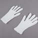 A pair of white Cordova Men's heavy weight lisle gloves on a gray surface.