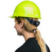 A woman wearing a green Cordova cap style hard hat with a ratchet suspension.