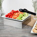 A Tablecraft stainless steel square bowl with vegetables and crackers on a table.