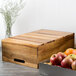 A Tablecraft acacia wood crate with apples and oranges in it.