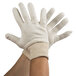 A pair of Cordova Men's white jersey gloves, one turned inside out.
