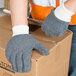 A person wearing Cordova loop-out gray work gloves and holding a box.