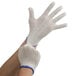 A pair of large natural cotton jersey gloves with blue trim on the wrists.