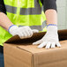 A person wearing Cordova medium weight natural cotton work gloves opening a box.