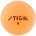 A close up of a Stiga 1-star orange ping pong ball.