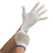 A pair of hands wearing white Cordova work gloves with blue trim.