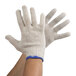 A pair of hands wearing Cordova medium weight natural polyester/cotton work gloves with blue trim.
