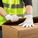 A person wearing Cordova medium weight natural polyester/cotton work gloves opening a box.