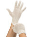 A close-up of a hand wearing a Cordova economy weight natural polyester/cotton work glove.