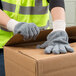 A person wearing Cordova gray jersey work gloves opening a box.