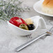 A white Villeroy & Boch bowl with olives, peppers, and other foods next to a fork.