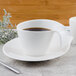 A Villeroy & Boch white porcelain saucer with a cup of coffee on it.