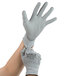A pair of hands putting on large gray Cordova Valor gloves.