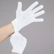 A pair of hands wearing white Cordova work gloves.