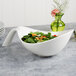 A white Villeroy & Boch deep handled bowl filled with salad on a table.