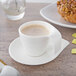 A Villeroy & Boch white porcelain saucer with a cup of coffee on a table.