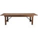 A Flash Furniture Hercules long brown wooden farm table with legs.