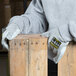 A person wearing Cordova Monarch cut resistant work gloves with split leather palms leaning on a piece of wood.