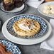 An Arcoroc Candour Azure porcelain brunch plate with waffles, bacon, and coffee on a table.