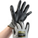 A pair of gray Cordova Monarch work gloves with black HCT nitrile palm coating on a hand.