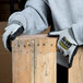 A person wearing Cordova Monarch gray and black work gloves holding a piece of wood.