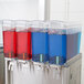 A row of Crathco beverage dispensers with blue and red liquid being poured.