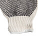 A white knitted work glove with black dots on the palm.