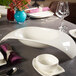A white Villeroy & Boch Urban Nature fruit traverse bowl on a table with plates and glasses.
