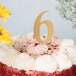 A white frosted cake with a gold number 6 on top.