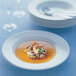A Villeroy & Boch white porcelain soup bowl filled with seafood and vegetable soup.