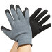 A pair of hands wearing Cordova gray and black latex palm coated gloves.