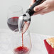 A person using a Rabbit aerating wine pourer to pour red wine into a glass.