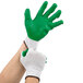 A pair of hands wearing Cordova green and white work gloves.