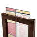 A menu in a walnut wood frame with an angled base.