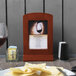 A Menu Solutions mahogany wood menu frame on a table with wine and chips.